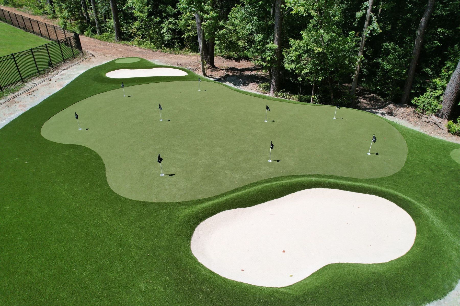 Multi-hole residential short-game facility with sand bunkers and tournament flags, built by Surface Evolution