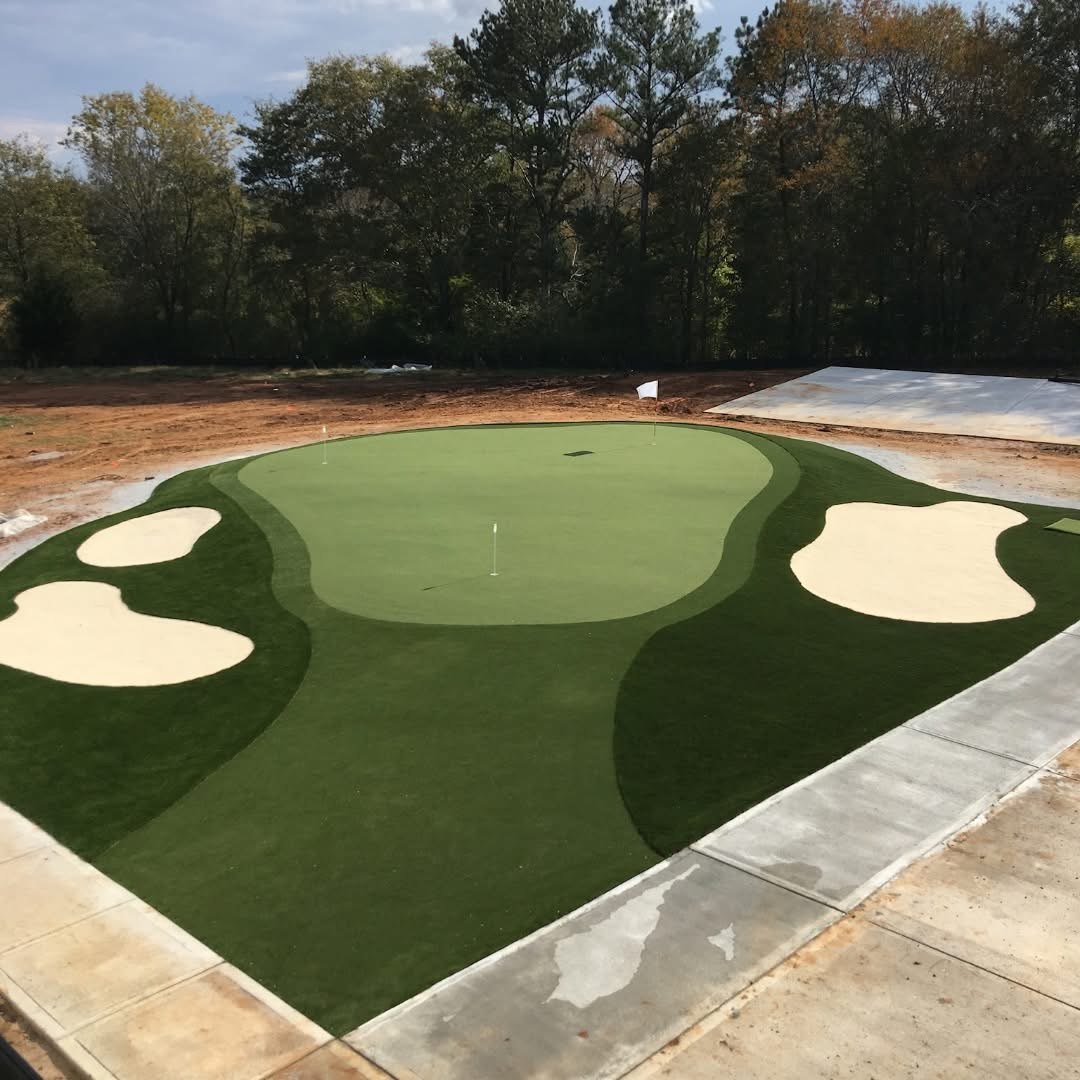 Sprawling residential short-game green with white sand bunker and backyard pool in the USA